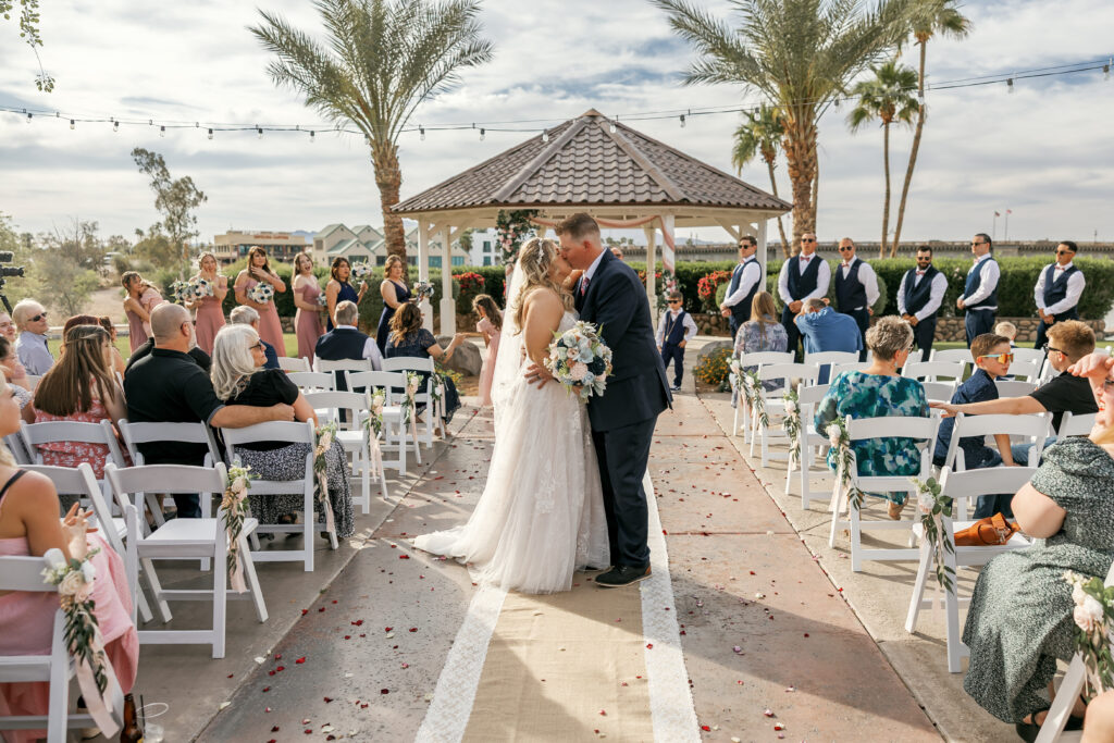 Bride and groom share their first kiss under a gazebo during their outdoor ceremony at London Bridge Resort in Lake Havasu, captured by Elona Shea Photography.
