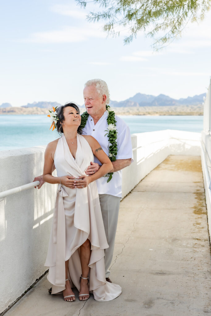 Couple embracing at Nautical Beachfront Resort in Lake Havasu, Arizona with waterfront views and desert mountains in the background