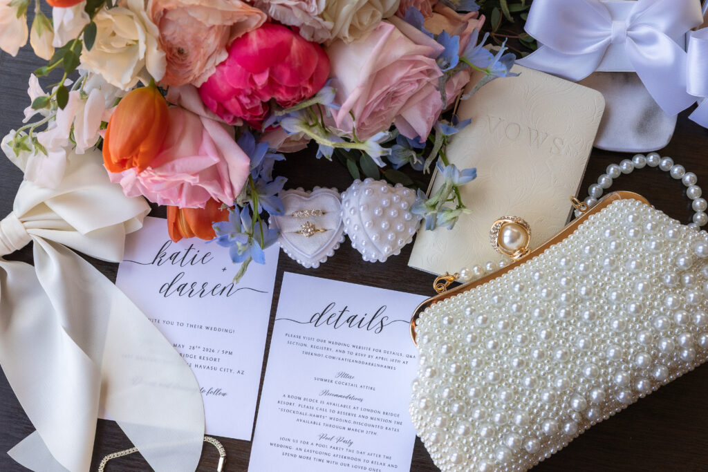 Katie and Darren’s wedding invitation, rings, pearl accessories, and colorful flowers.