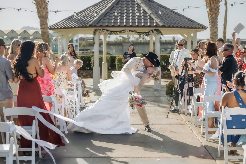 Katie and Darren share a dip kiss during their London Bridge Resort wedding ceremony exit.