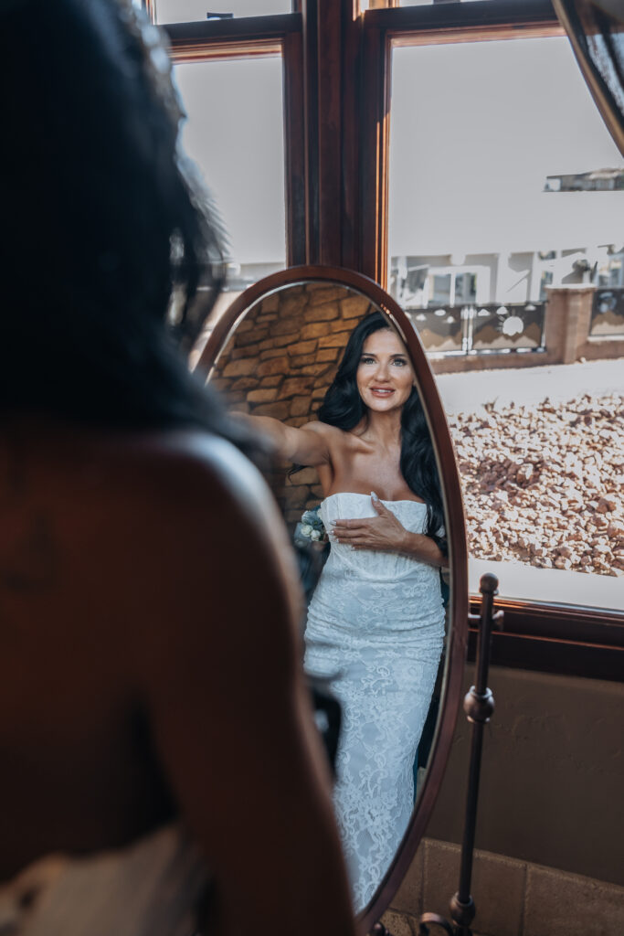 Lizzy looking into a mirror while getting ready for her wedding at The Refuge
