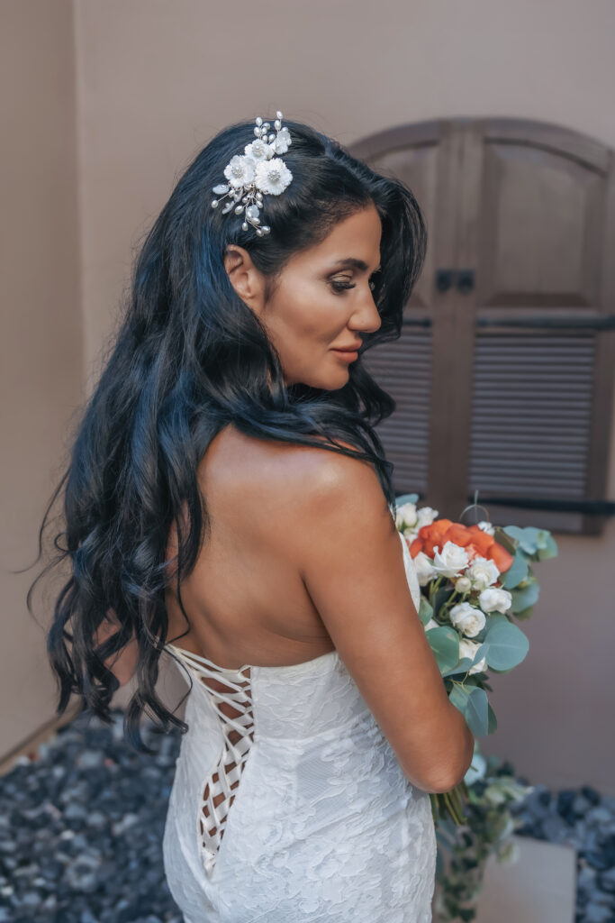 Lizzy showing the lace-up back of her wedding dress while holding her bridal bouquet