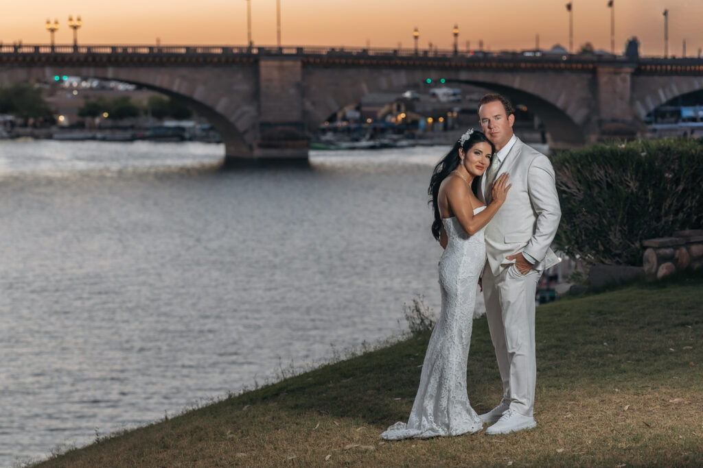 Paul and Lizzy posing by the water at sunset with the London Bridge behind them in Lake Havasu